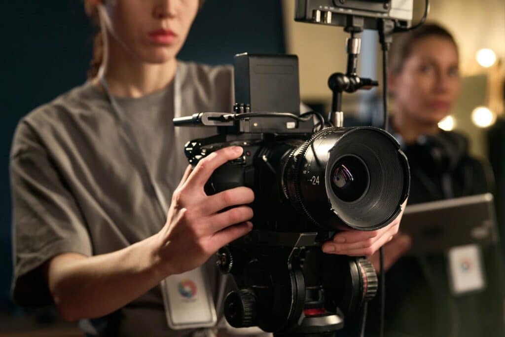 BloomHouse Media Studio: Female videographer holding a professional video camera, filming a video production project.